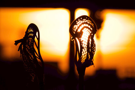A silhouette close up of  Sunset Lacrosse Sticks, under an orange sunlightの写真素材
