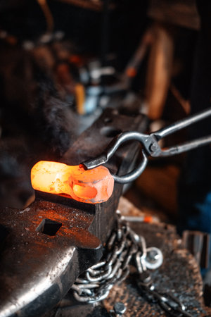 A vertical shot of forging a small piece of metal in the workshop with a blurry backgroundの写真素材