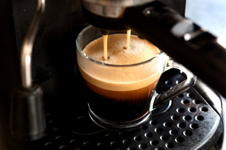 A high angle closeup of a mug and a coffee machine in the processの写真素材