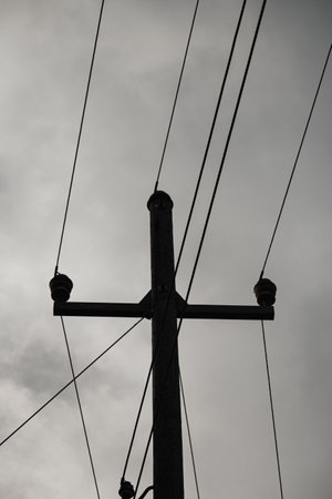 A vertical shot of an electric pole on the background of the gloomy skyの写真素材