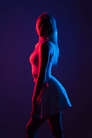 A portrait of a young Canadian woman in sportswear posing under blue and red lights in a dark studioの写真素材
