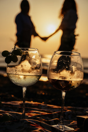 A vertical shot of two glasses of wine with a couple in the backgroundの写真素材