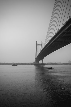 A vertical shot of a bridge James Prinsep Ghat in grayscale in Kolkata, Indiaの写真素材