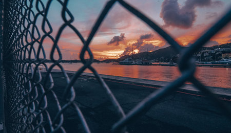 The sunset in the bach behind the metal fence