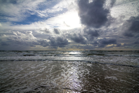 A closeup of beach waves against a cloudy sky