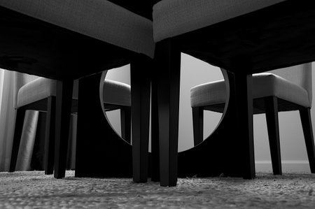 A grayscale shot of modern chairs and a table in a houseの写真素材