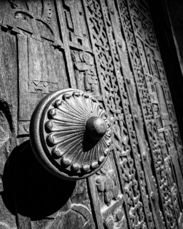 A grayscale shot of an ancient Armenian door of the church with different carved ornamentsの写真素材