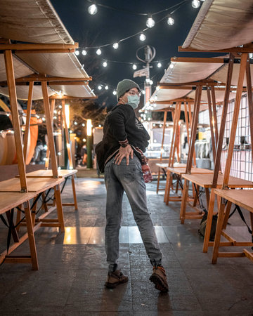 A vertical shot of a young male posing sexy near outdoor wooden stands at nightの写真素材
