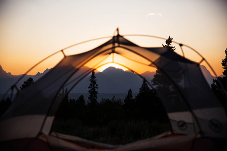A tent during the beautiful sunset and mountains in the backgroundの写真素材