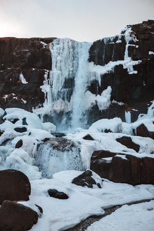 A vertical shot of a waterfall with clear blue water in Icelandの写真素材