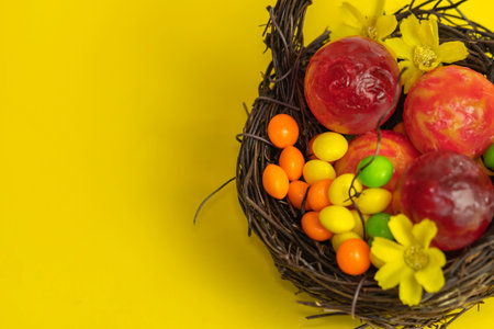 A top view of a basket with fruits and flowers on the yellow background