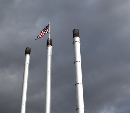 The national flag of the USA on the pole against a cloudy sky on a sunny day