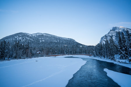 A chilling view of a frozen river and forest landscape under a clear blue skyの写真素材