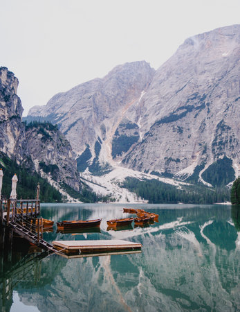 A vertical shot of boats on an icy lake near snowy cliffs in Italyの写真素材