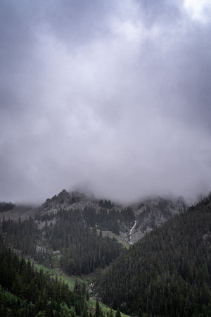 A vertical shot of mountains under the cloudy sky