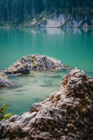 A vertical closeup shot of rocky formations in a green blue lake in Italyの写真素材