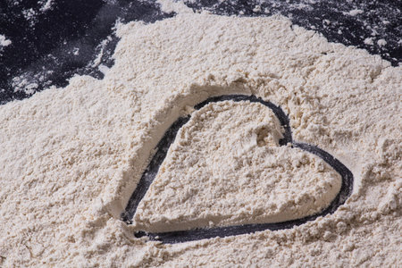 A closeup of the heart shape on the table covered with flour.の写真素材