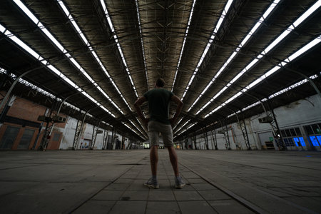 A male standing in an empty hall of an industrial buildingの写真素材