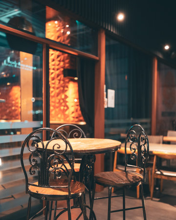 An empty cafe interior with a round table and chairs with a view to the evening streetの写真素材
