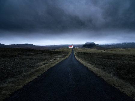An asphalt road in the middle of the field on a cloudy eveningの写真素材