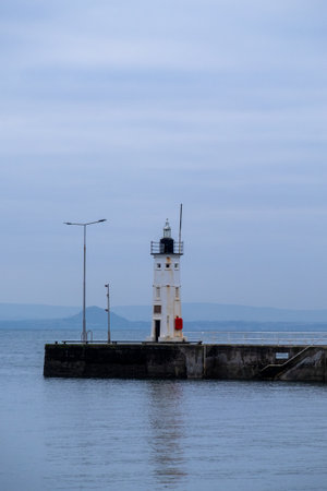 A vertical shot of a lighthouse on the edge of a portの写真素材
