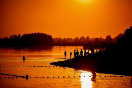 The silhouettes of people by the lake at the sunsetの写真素材
