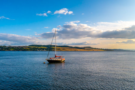 A beautiful scenery of a small sailboat on the river and a cloudy sky, Tay in Scotlandの写真素材