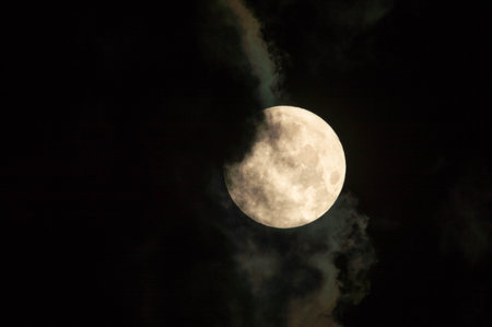 A full moon glowing on a cloudy dark sky