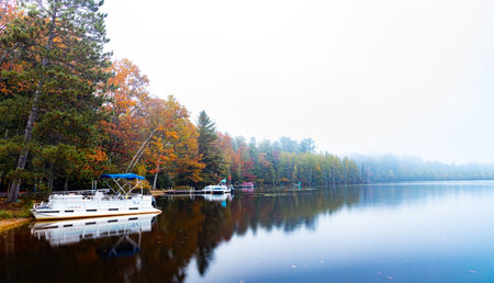 A lake surrounded by forest in the fall colors on a foggy day