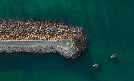 An aerial top view of a lighthouse on a geological formation in the sea
