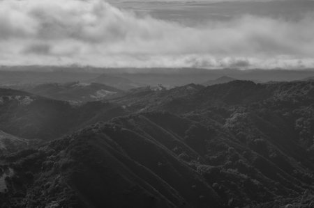 A monochrome shot of rough mountains under a cloudy sky