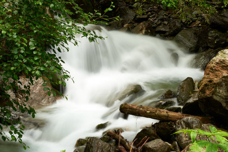 A breathtaking waterfall in the forest amid dense vegetation and big rocks