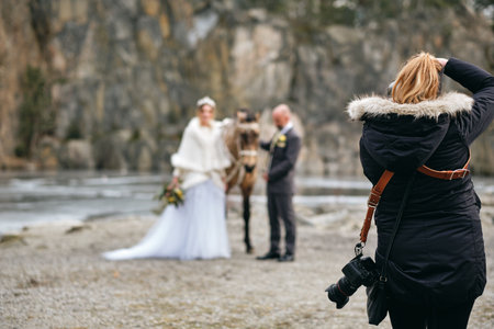 A photographer taking pictures of the bride and the groom with a horseの写真素材