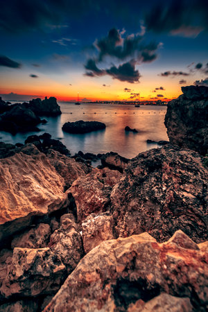 The beautiful sunset at the rocky St. Paul's Bay in Maltaの写真素材