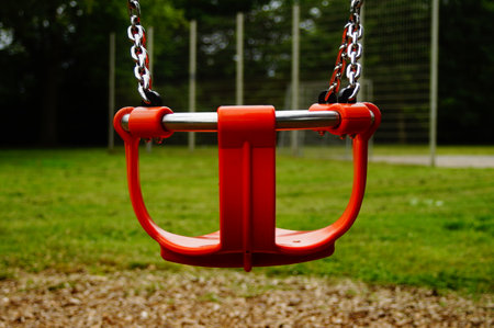 A lonely children's swing for smaller children in an deserted playground on a rainy day. A nice...