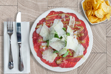 A top view of a Carpaccio dish on a white plate and Tableware on a decorated tableの写真素材