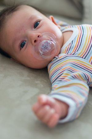 A vertical shot of a Caucasian baby boy lying comfortably with a pacifier in his mouth in Polandの写真素材
