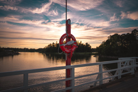 The view of the pier with a lifebuoy on a pole at sunset.の写真素材