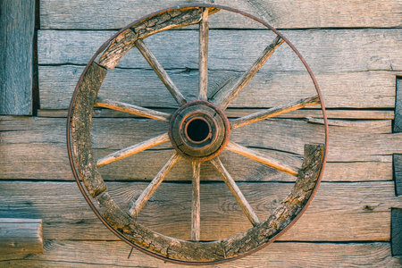 A closeup of an old wooden wheel on a wooden wallの写真素材