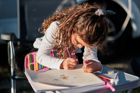 A Caucasian girl coloring on paper outdoorsの写真素材