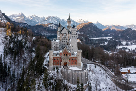 A scenic shot of the Neuschwanstein Castle in Germany surrounded by snowy mountain forestsの写真素材