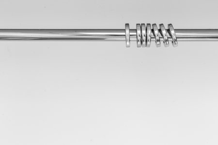 A closeup shot of a shiny metal curtain rod with rings isolated on white backgroundの写真素材