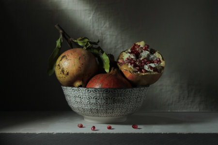 A closeup of ripe pomegranates in a bowl on the table against a wallの写真素材