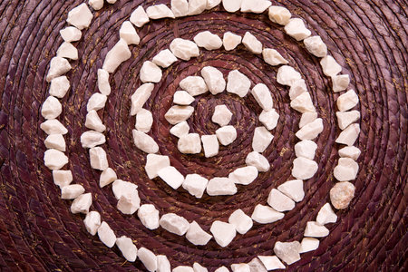 The Spiral Life Symbol sacred symbol written with white stones over a rustic purple textureの写真素材
