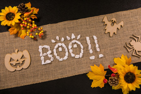 A top view of the Boo!! word and artificial flowers on a linen fabricの写真素材