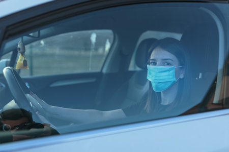 A Caucasian female in a face mask driving a carの写真素材