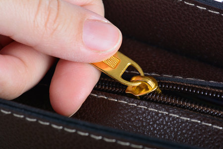 A Caucasian hand opening brown leather bag zipperの写真素材