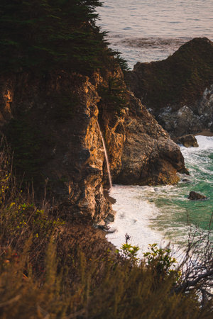 A view of a waterfall off of the Pacific Coast Highway in Big Sur, Californiaの写真素材
