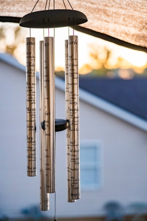 A vertical shot of Windchimes hanging outdoors on a blurred background
