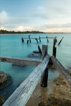 A vertical shot of an old weathered pier by the sea at sunsetの写真素材